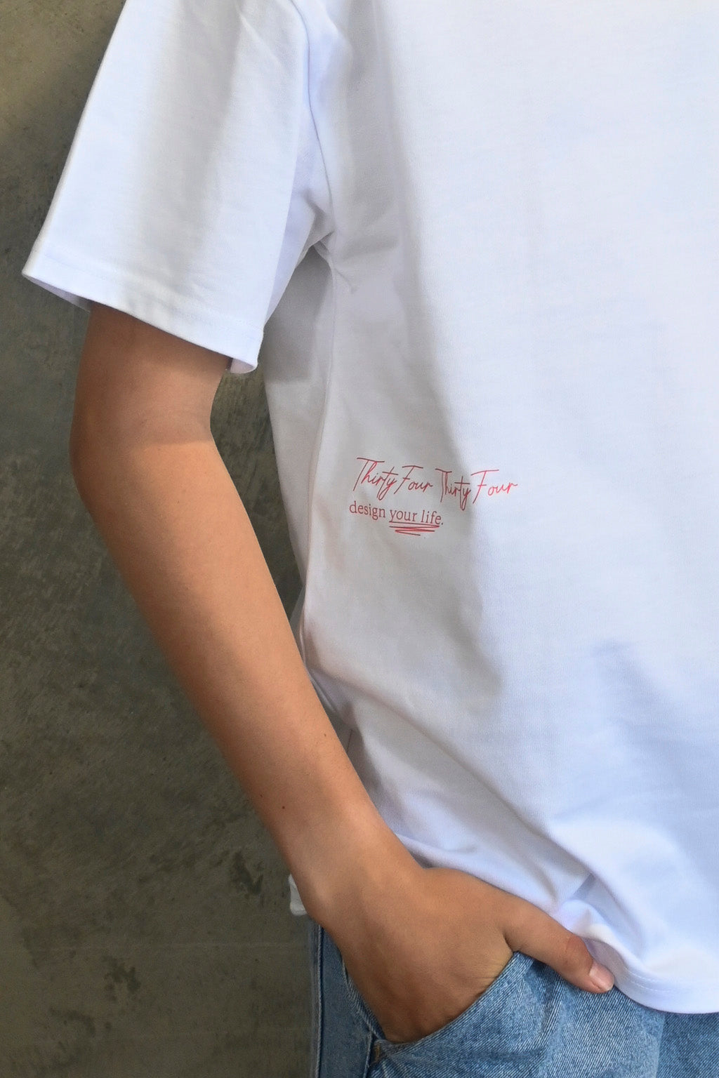 Close-up of Thirty Four Thirty Four red logo and design your life text on white tee