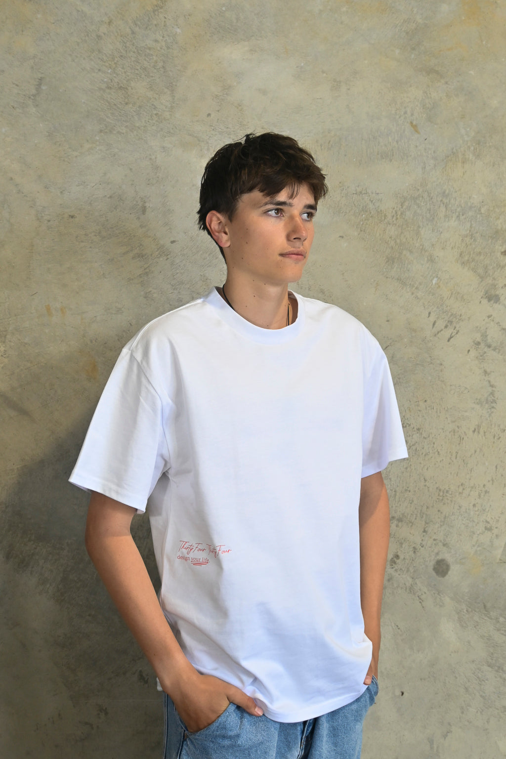 Model wearing white oversized heavy tee by Thirty Four Thirty Four with red logo print