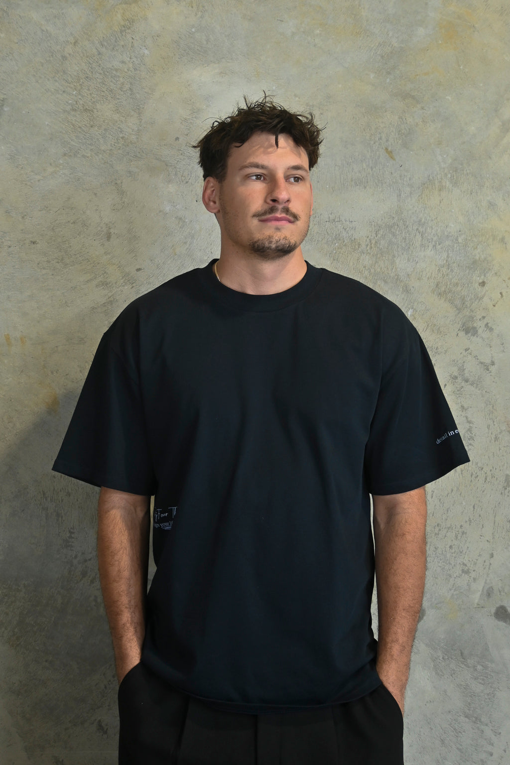 Male model styling dark navy oversized streetwear t-shirt with minimalist branding