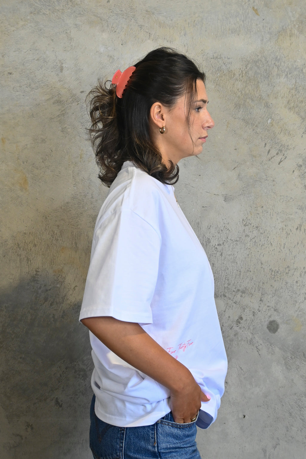 Model wearing white oversized heavy tee by Thirty Four Thirty Four with pink logo print