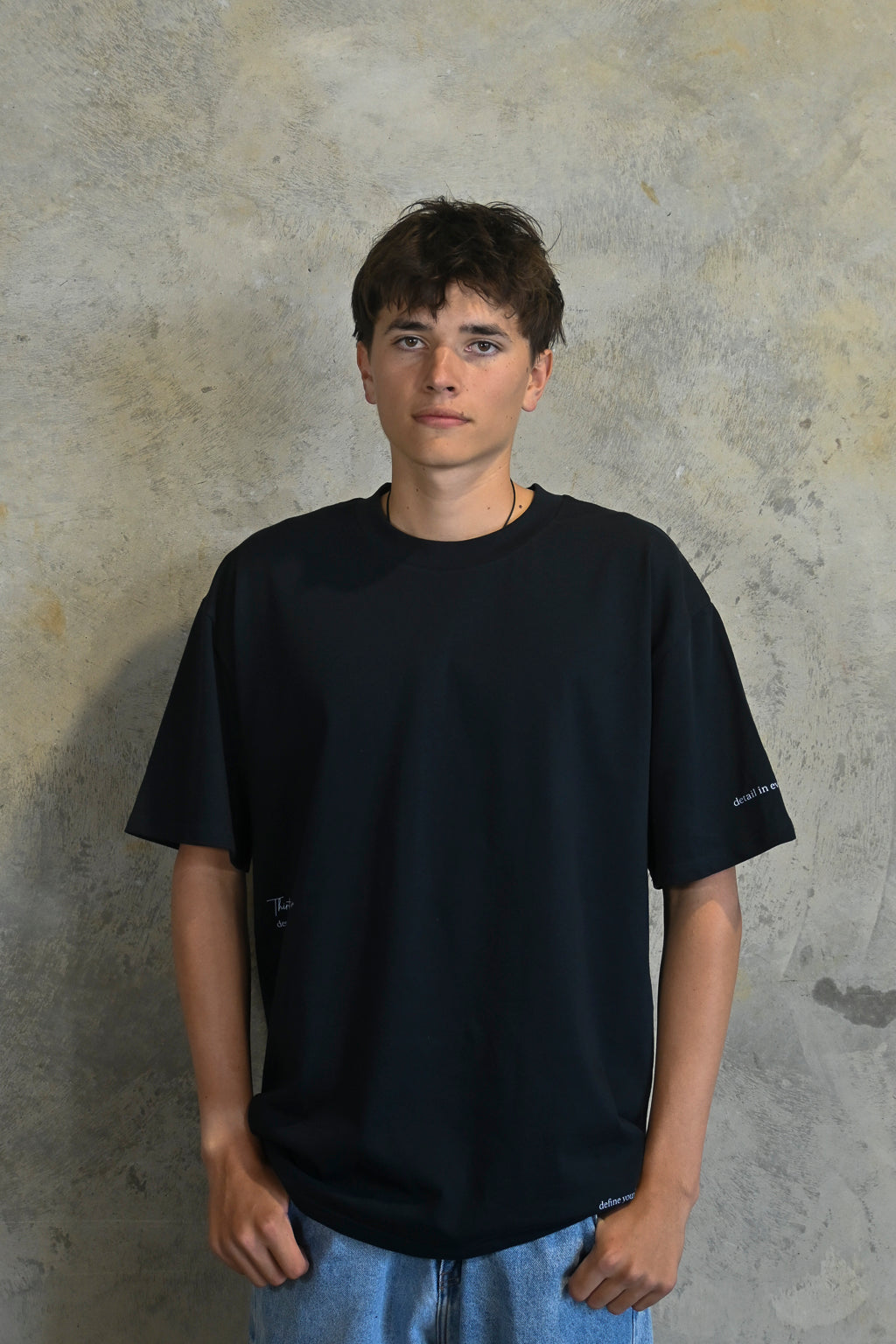 Male model styling dark navy oversized streetwear t-shirt with minimalist branding